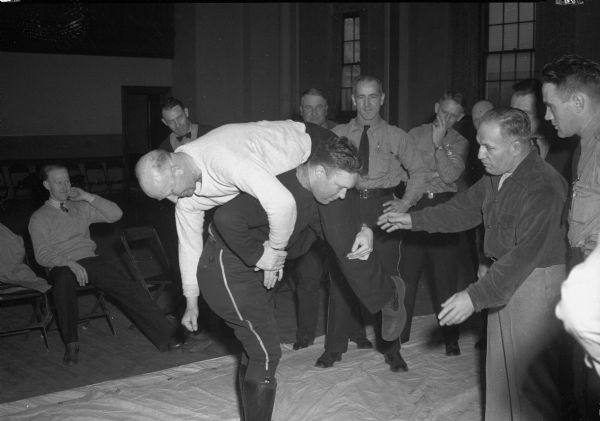 Jimmy Demetral, Madison wrestler, teaching Officer Robert O'Brien to do an "airplane spin" toss on Officer Keith Ackley. Fifty-five Madison Police Department officers were enrolled in a five week Judo course.