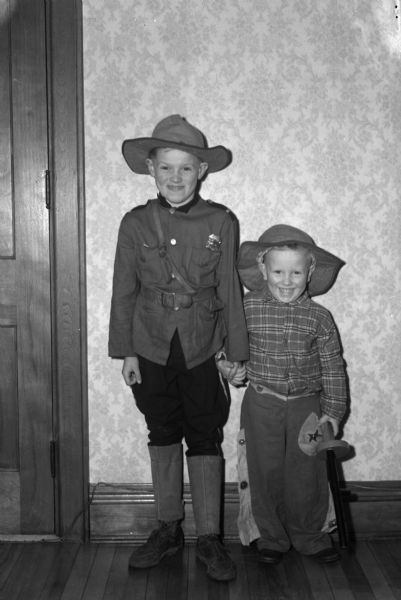Two young boys dressed in costumes as a soldier and a cowboy.