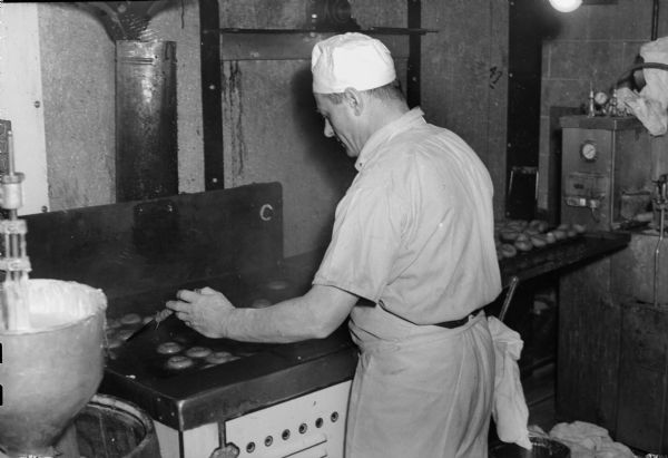 Bread company employee making donuts, possibly at the Heilman Baking Company.