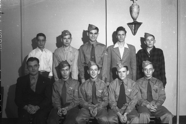 Nine Air Scouts (Boy Scouts) and their leader, Ernfred Romare. Back row, left to right are Keith Pope, Fred Peterson, Bill Harks, Francis Dirienzo, and Tom Morris; front row are Squadron Leader Ernfred Romare, Alan Wade, Dick Hauser, Bill Doudna, Jr., and Jim Henry. They are part of the Air Squadron 242, sponsored by the Independent Order of Odd Fellows, Madison Branch.
