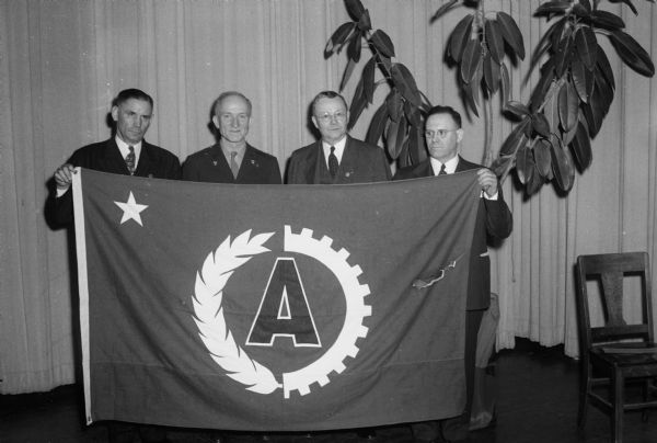 Columbus Foods Corporation received an "A" for achievement award flag for food production and canning. Taking part in the ceremony, left to right are: J.L. Albright, corporation secretary; Brig. Gen. Carl A. Hardigg, chief of subsistence, quartermaster corps, office of quartermaster general, Washington, D.C., who presented the award; F.A. Stare, corporation president; and L.C. Richards, assistant factory superintendent, an employee representative.