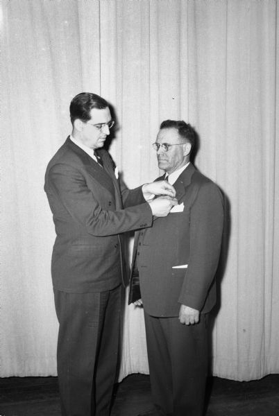 L.C. Richards, assistant factory superintendent of the Columbus Foods Corporation, receiving the first "A" Achievement award pin from Donald E. Smith, deputy regional director, office of distribution, War Food Administration (WFA), Chicago. Richards had been with the company for more than 30 years.