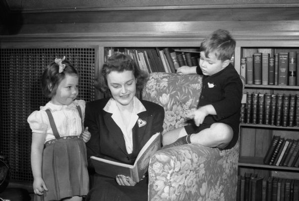 Martha Hardin reading to Janet Brahn and Betty Thomsen at the nursery school established on the third floor of the home of University president, Charles A. Dykstra, 130 North Prospect Avenue, Madison. The nursery school was established by the Junior Division of the University League.