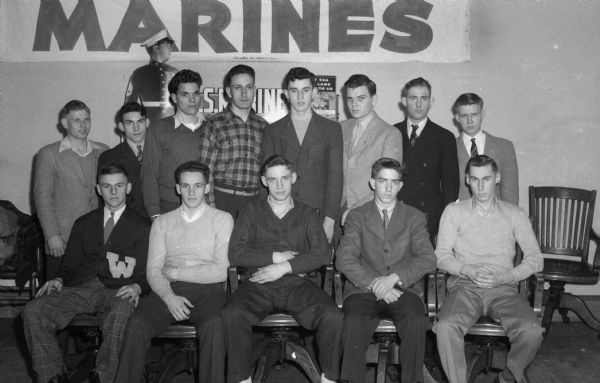 Thirteen Madison-area 17-year-old youths are accepted for enlistment at the Madison Marine Corps station, before leaving for Milwaukee to be sworn into the Marine Corps on inactive status. Seated, left to right, are Donald P. Gerth, Watertown; Wendolyn H. Volbrecht, Baraboo; Eugene T. Harms, Baraboo; Lawrence E. Brennan, Dodgeville, and Philip G. Hoff, Mt. Horeb.  Standing, left to right, are Virgil Butt, Janesville; Clement B. Ash, Milton Junction; Robert E. Millard, Portage; Richard C. Thompson, Argyle; Francis X. Veserat, 925 Lake Court; William C. Vilbrandt, 1207 Vilas Court; Arthur E. Hebner, Beaver Dam, and Arnie C. Rortvedt, Route 1.