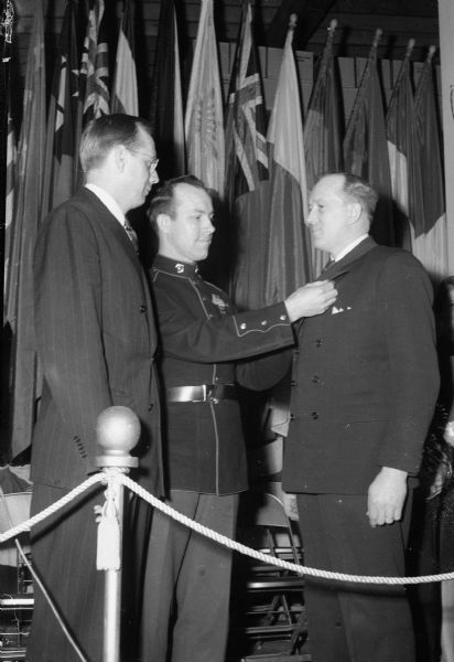 Gordon Gunderson, State Supervisor, Office of Distribution, War Food Administration, watches as Corp. David Moul, Lodi, pins a citation on the lapel of Gordon Packard, employee representative of the Arlington plant of the California Packing Corporation. The award was given for outstanding achievement in war food production.