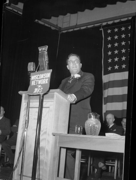 Wendell Willkie giving a campaign speech in 1944 in the Richland Center High School gymnasium. There is a WIBU microphone with a sign for Wisconsin Network - MBS (Mutual Broadcasting System ?) in front of the podium.