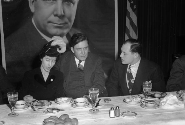 Republican Presidential candidate Wendell Willkie with Mr. and Mrs. Louis J. Fellenz Jr. (R-Fond du Lac), sitting at a banquet table in front of a large photo poster of Wendell Willkie, during Willkie's 1944 campaign.