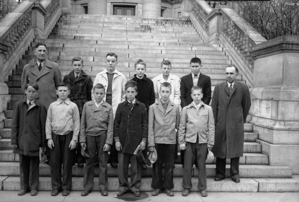Eleven boys, winners of a contest for <i>Wisconsin State Journal</i> newspaper carriers, and their supervisors from the circulation area standing on the steps of the Wisconsin State Capitol building.