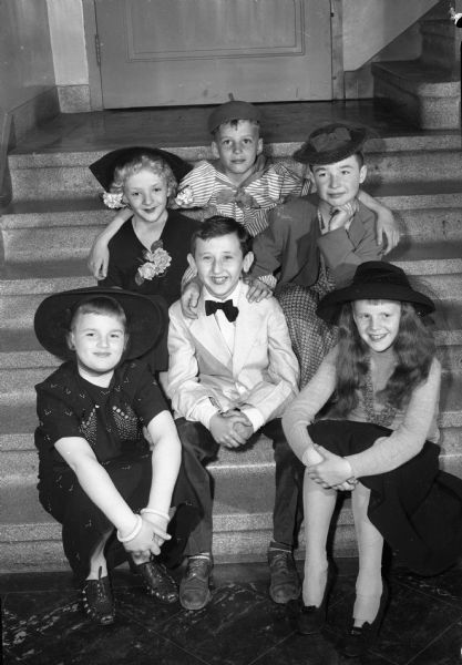 Highlight of the entertainment at the final dancing party of the Junior Cotillion club of Wisconsin High School was the Frank Sinatra act put on by members of Cub Scout Pack 3 from Lakewood School, Maple Bluff. In the picture, Bill Spoentgen, who took the part of "The Voice," is shown surrounded by a group of his "feminine" admirers. The trio seated in back of "Frankie" includes Dick Plater, left, Donnie Fauerbach, center, and Tom Charmley, right. The two "sirens" in the front row are Ronald Klemm, left, and Carl Weston, right.