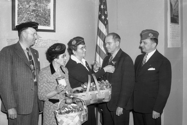 Mayor Halsey Kraege buys the first poppy from Mrs. John Coyne, Veterans of Foreign Wars Poppy Day sale chairman of the VFW Auxiliary. Left to right: Joseph Baer, American Legion, Mrs. E.C. Gerry, American Legion Auxiliary, Mrs. Coyne, Mayor Kraege, and Jacob Mintz, Veterans of Foreign Wars drive chairman.