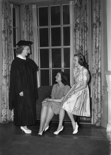 Three Pi Beta Phi graduates, left to right: Mary Jean Zentner, Wauwautosa, wearing cap and gown, Jo Ann Rose, Decatur, Illinois, and Mary Enneking, Madison.