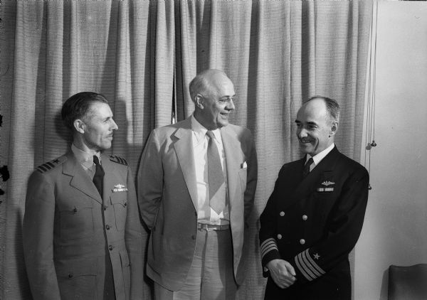 Captain Arthur S. Adams, director of the Navy's administration division of training, with from left to right: Commander Leslie K. Pollard and University President C.A. Dykstra.