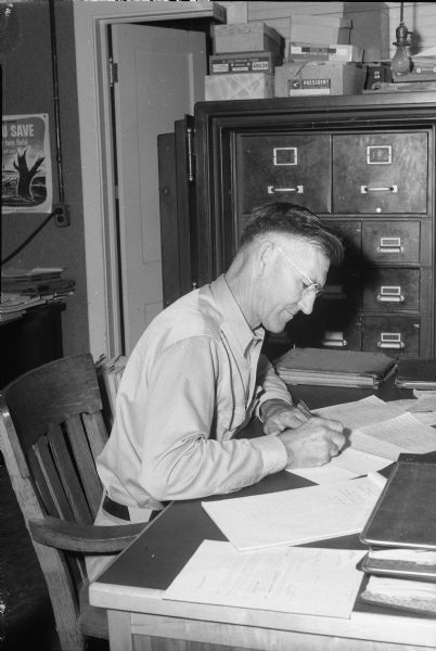 Freeman Clevidence, Director of Dane County Farm Bureau Cooperative, 301-303 South Paterson Street, sitting at his desk.