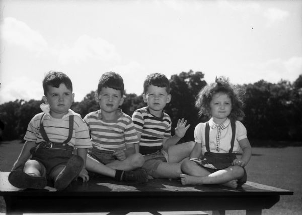 The four Wyngaard children, from left to right: Tim, John, Michael, and Judy, sitting on a picnic table in Vilas Park.