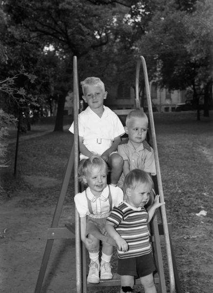 Outdoor group portrait of the four Cantwell children of 2801 Monroe Street, on a slide at Edgewood School. From top: Michael, Jeffrey, Connie, and Roger.