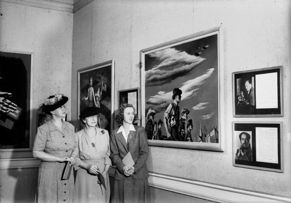 Mrs. Marshall Browne, Sarah Ross, President of the Madison Art Association, and Lovey Pond, member of the Memorial Union gallery committee, standing in front of "There's Work to be Done," by Georges Schreiber at a Memorial Union exhibit of paintings executed for use on war posters.
