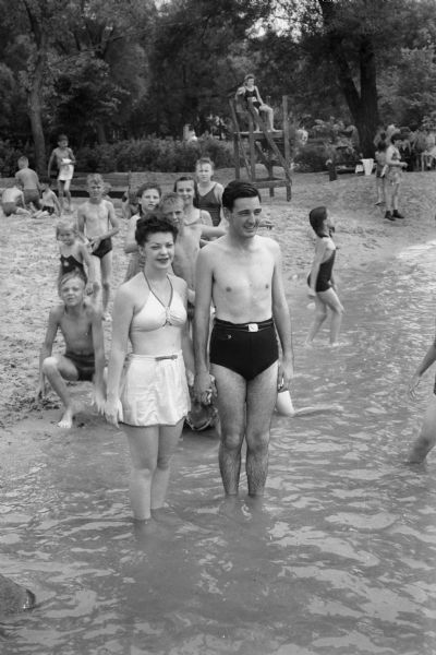 Private Fred Schneider and wife with crowd in the water at a beach.