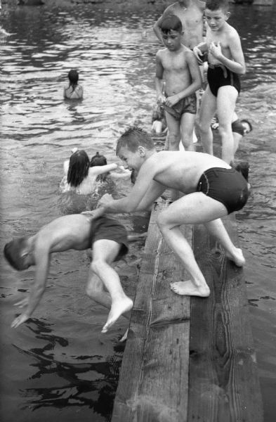Billy Wiedenbeck pushing Wally Britton into the water from a swimming platform.