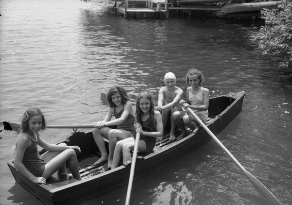 Five girls in a row boat on Lake Mendota at the YWCA's Camp Maria Olbrich. Seated left to right: Volala Still, Jane Botham, Doris Elliott, Gloria Trader, and Beulah Jeanne Roth.