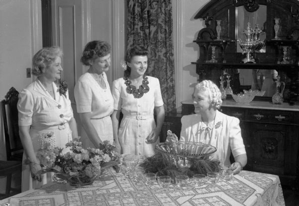 League of Women Voters garden party attended by more than 1,000 people. It was held at the Governor's Residence, 130 East Gilman Street. At the punch table are Mrs. Walter Goodland (Madge Goodland), Mrs. H. Kent Tenney (Jeanette Tenney), Mrs. W.E. Tretlin, (Gladys Tretlin), and Mrs. Oscar Rennebohm (Mary Rennebohm).