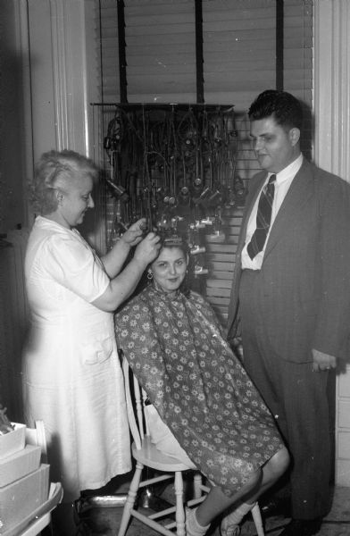 Philip John Dumbleton, his mother Mrs. Ruth Dumbleton, and client Bernadyne Hogan  photographed in one of two beauty shops he owns. Mr. Dumbleton who is blind, also operated a rooming house at the University of Wisconsin-Madison, and is qualified to practice as an attorney-at-law.