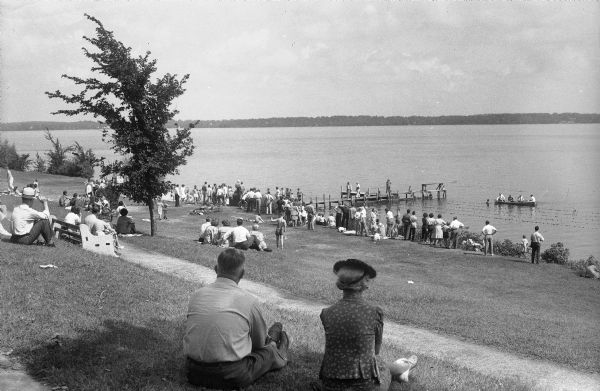Onlookers on slope of B.B. Clarke Beach looking out to the lake to watch a swim meet.