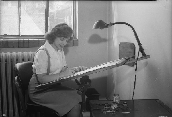 Unidentified woman sitting at a drawing board, possibly Miss or Mrs. Younger.