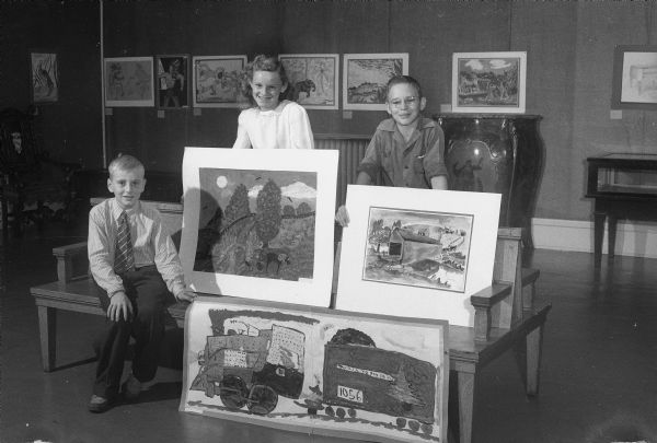 Allen Steinmetz, 4th grader at Marquette, Berry Cass, 6th grader at Emerson, and Richard Bender, 9th grader at Central Jr. High School, with their paintings which were being exhibited in the "Children Look at Wisconsin" exhibition at the Gregory Room of the State Historical Society.  The exhibit features pictures selected from bi-monthly exhibitions held in the children's room of the Wisconsin Historical Museum throughout the past year.