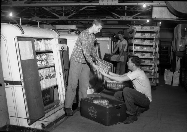 Three high school students loading a truck at Gardner Baking Company. From left: Edward Witek, Central High, Russell Kundert, Vocation High, and in the background, Frank Wood, Central High. These students divide their days between school work and work about town under a work-credit plan devised by the Board of Education, which is considered one of the foremost in the nation. This work-credit program using students was necessary due to the shortage of workers during World War II.
