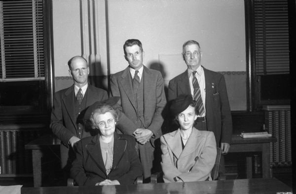 Five Dane County Residents who are taking an active part in the county War Fund drive in the area outside of metropolitan Madison. Standing from left to right: Lester E. Caldwell, Morrisonville; John Mell and Andrew J. Mell, DeForest. Seated from left to right: Mrs. William Maher and Mrs. L.A. DePolis, both of Route 1. Madison War Chest contributes money to the National War fund to support 21 voluntary agencies working for GIs still in service, including USO, and the Allies.