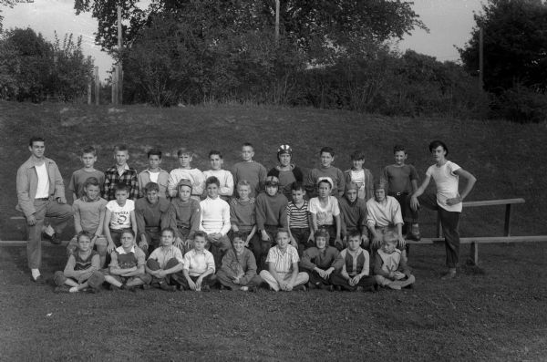 Group portrait of midget football team, the West End Tigers, coached by Truax Field Pvt. Ralph Deck, from Chattanooga Tennessee, with Junior Coaches Harold Currie, left, and Buckley Brown, right. The captains were Ted Blaskney, David Hoeveler, and Malcolm Ross.