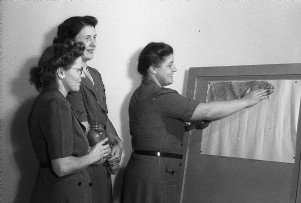 Mrs. Roy F. Engel (Leila), an officer of the Scout Leaders Club, demonstrating a finger painting project that will be taught to girl scouts, to Mrs. C.S. Greve (Martha), a Brownie Scout leader at Lowell School, and Mrs. Harry Lehman (Mabel), Girl Scout leader at Allis School.
