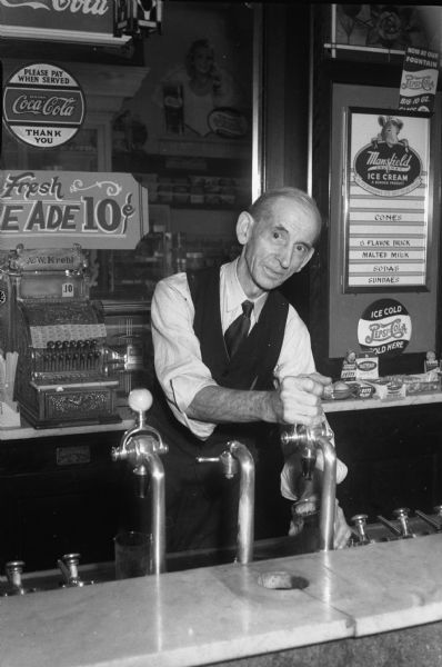 Seventy-six-year old Henry L. Krehl, believed to the be city's oldest soda jerk, at the soda fountain of his brother August W. "Doc" Krehl's drug store, 408 E. Wilson Street. Young soda jerks were not to be found during these war days.