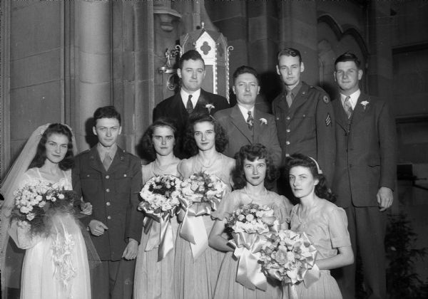 Group portrait of bride Catherine Marie Endres and groom Corp. Gerald John Sullivan with their attendents: Agnes Endres, maid of honor, and bridesmaids Margaret Sullivan, Eunice Endres, and Rose Caroline Endres; best man Joseph A. Sullivan, and ushers George Sullivan, Sgt. Wendell Palmer and Clifford Kohlman. Taken in St. Paul's University chapel.