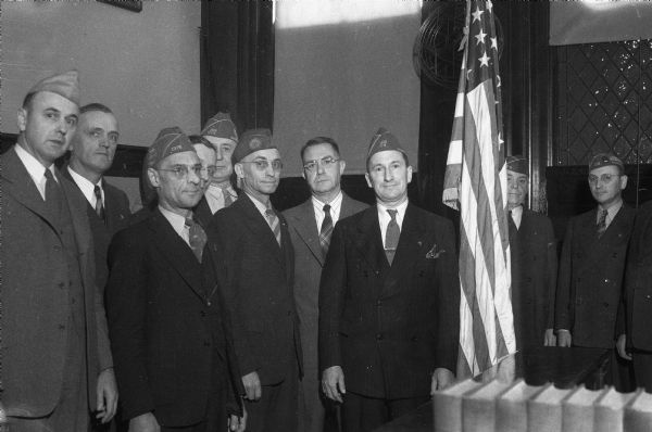 Group portrait of ten members of the Marion C. Cranefield post No. 1318 Veterans of Foreign Wars presenting a United States flag and staff for use at the Dane County Circuit Court branch No. 1. From left to right are: Assemblyman Lyall T. Beggs, Deputy Albert Amble, Herbert Meiller, Russell Williams, Sheriff John Arnold, Edward J. Watland, Circuit Judge Alvin C. Reis, Post Commander Albert Nonn, R.S. Schiebel, and Paul W. Lappley.