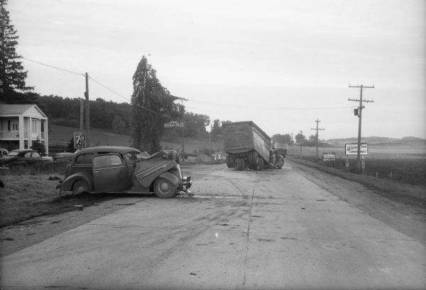 Scene of wrecked car and semi-trailer truck in front of Alma's Inn, 5068 Highway 12-13. Injured in the accident were five men en route to work at the Badger Ordnance Works at Baraboo.  The men are: Albert E. Smith, 39, Platteville; Horace Berg, 43, Belleville; Norman Harper, 42, Belleville; E.M. Disch, 49, Belleville; and Carlton S. Burke, 41, Belleville. The driver of the truck, Norman R. Everson, 35, Eau Claire, was uninjured and helped rescue the occupants of the car. Alma's Inn was torn down during the expansion of Highway 12 which was completed in 2005.