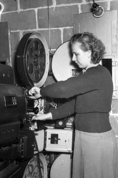 Jean Larson, at the time one of three women projectionists in the country, operating the movie projector at the University of Wisconsin Memorial Union Play Circle. Traditionally this position was held by a man before World War II.