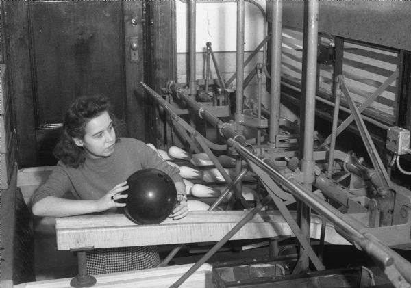 Virginia Rae Miller, a pinsetter at the Lathrop Hall bowling alley, about to return a bowling ball.  Traditionally, this work was done exclusively by men before World War II.