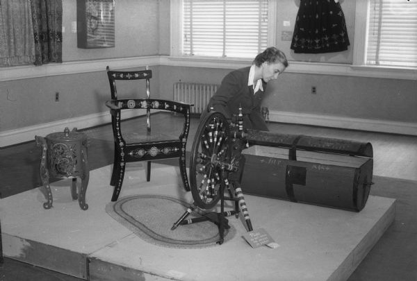 Joyce Elmer, Memorial Union gallery committee chairman, inspecting an antique Norwegian chest as part of an exhibit of Elaine Smedal's "Norwegian Wisconsin as a Source of Design." Elaine Smedal arranged the exhibit as part of her Masters thesis.