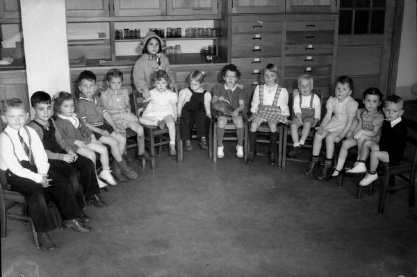 Children participating in a thimble party at the Shorewood Hills School while their mothers participated in the annual Madison Woman's Club benefit party. From left are Frederick Fitchen, son of the J.A. Fitchens; Tommy Brennan, son of the K.T. Brennans; Kathleen and Roger Coffman, daughter and son of Mr. and Mrs. Ramon Coffman; Mary Alicia Brandt, daughter of the Myron C. Brandts; Bonnie and Cynthia (standing) Curreri, daughters of the Anthony Curreris; Nancy Wilson, daughter of the J. Robert Wilsons; Barbara Sue Cohen, daughter of the E.B. Cohens; Margaret Ann Sy, daughter of the R.W. Sys; Fritzie Wolff, son of the C. Frederick Wolffs; Gail Cooper, daughter of the Garrett A. Coopers; Dianne Dodd, daughter of the Robert H. Dodds; and Roger Anderson, son of the K.W. Andersons.