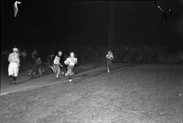 Madison East High School quarterback, Don Stevens, scoring a touchdown against Madison West High School with halfback, Bob Somerville, close behind. The game ended in a 7-7 tie.