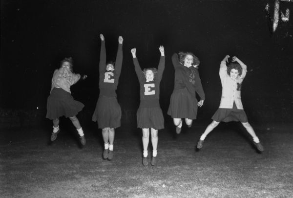 East High School cheerleaders cheering during an East-West High School football game that ended in a 7-7 tie. From the left are: Virginia Seldal, Irene Yust, Audrey Powers, Joyce Binger, and Betty Bailey.