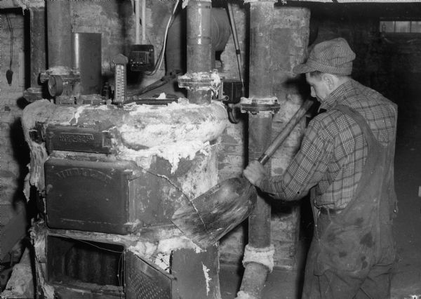 Unidentified man from A.M. Toussaint, heating contractor, fixing a furnace boiler.