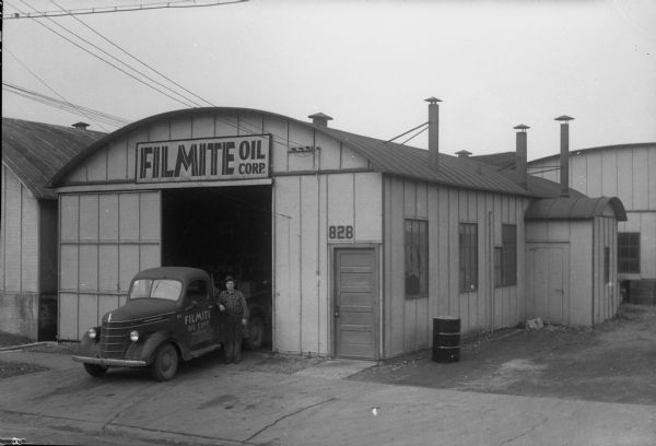 Madison branch of the Filmite Oil Corporation building (a Trachte metal building), located at 828 East Main Street.  Also pictured is W.K. Wilson, warehouse foreman, standing next to the company's service truck.