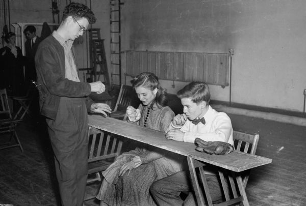 West High School student production of "Our Town" during the drug store scene, with Kenneth Paine, druggist, Virginia Baldwin, and Joel Salter.