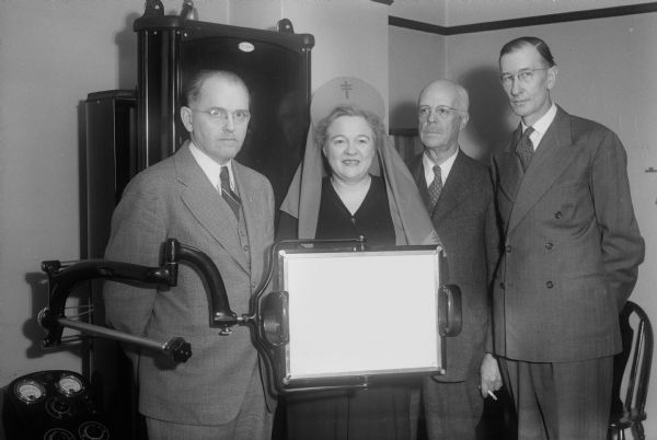 The presentation of a fluoroscope purchased by the Madison Tuberculosis Association to the City of Madison Health Department. Shown left to right are Mayor Halsey Kraege; Mrs. George R. (Mabel) Holdhusen, chair of the Christmas seal sale campaign; Doctor F.F. Bowman, City Health Officer; and Harry G. Marsh, Tuberculosis Association president.