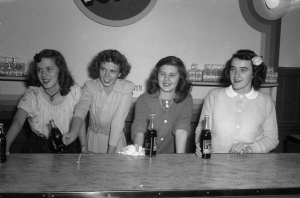 Four girls serving cokes at the opening of the LOFT. Left to right: Mary Fahlberg, 1705 Jefferson Street; Dorothy Fox, 1705 Jefferson; Alice Harms, 202 N. Allen Street; Georgia Hass, 2372 West Lawn Avenue, all West High School students.