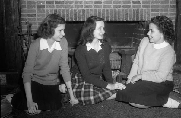 Three girls in front of the fireplace in the Blue Room at the LOFT. The following students are from Wisconsin High School, left to right: Kate Tegge, 149 West Wilson Street; Louise Frederick, 102 East Lakeside Street; Rita Wolf, 520 South Orchard Street.