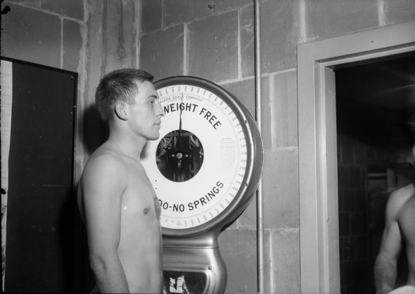 Ten individual portraits of University of Wisconsin football players each standing on a Toledo No-Springs scale. Included are: Joe Campbell, John Davey, Clarence Esser, Wray George, Jack Haese, Nick Holmes, Roger Laubenheimer, Jack Mead, Martin Meyer, Jerry Thompson. Also included is a close-up of the Toledo scale.