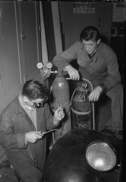 Automotive Mechanics class at East High School. Carl La Belle welding a fender with David Beale looking on.